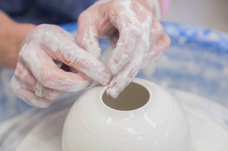 Person throwing clay on the wheel